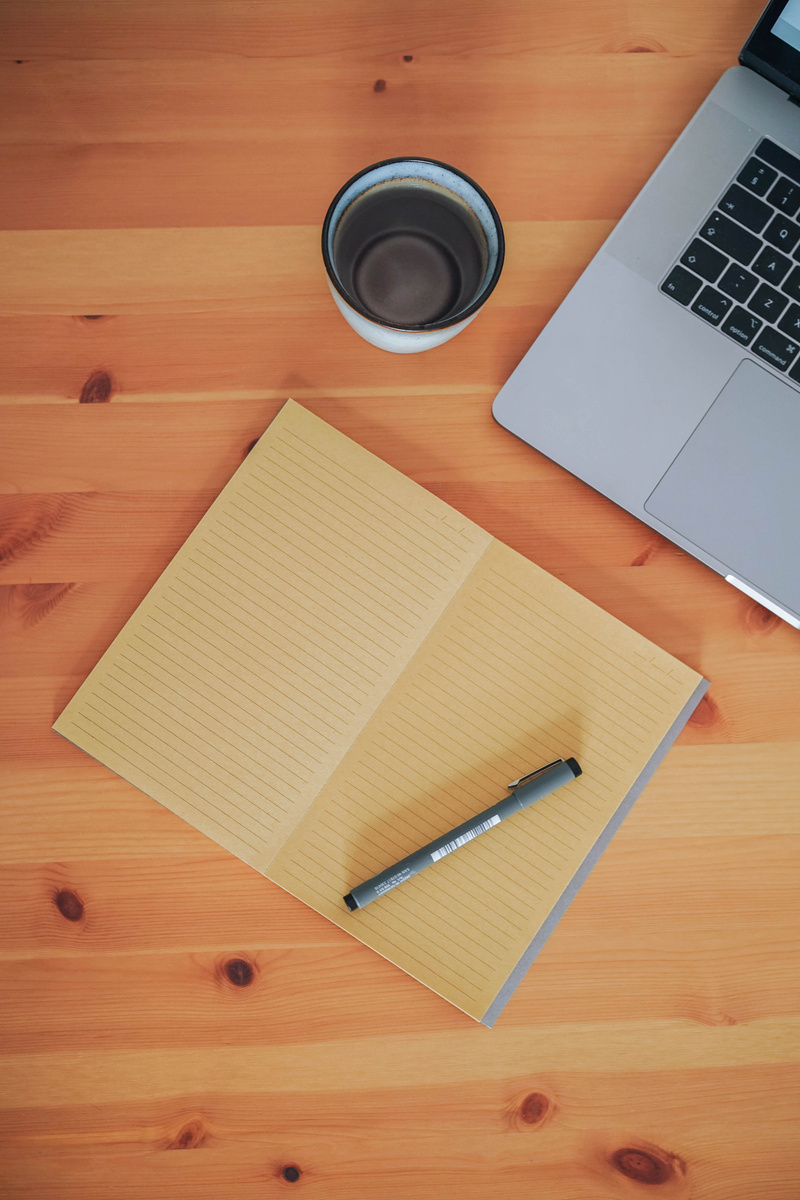 Laptop and Notebook on Wooden Desk